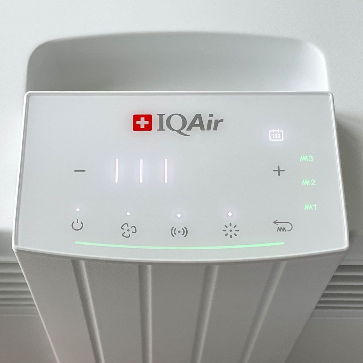 Nahaufnahme des Bedienfelds des IQAir HealthPro 100 XE Luftreinigers mit Touch-Symbolen und grüner Leuchtanzeige