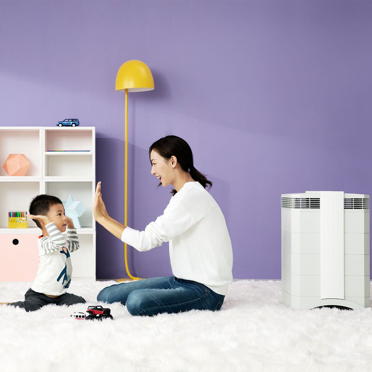 IQAir HealthPro 100 XE Luftreiniger in Weiß im Kinderzimmer, Mutter und Kind spielen davor