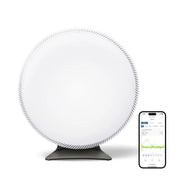 IQAir Atem X Luftreiniger, runde weiße Front, daneben Smartphone mit App-Verlaufsanzeige