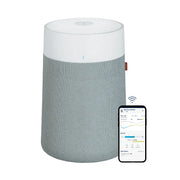 Blueair Blue Pure 311i Max Luftreiniger mit grauem Stoffbezug und weißem Oberteil, daneben Smartphone mit App-Anzeige