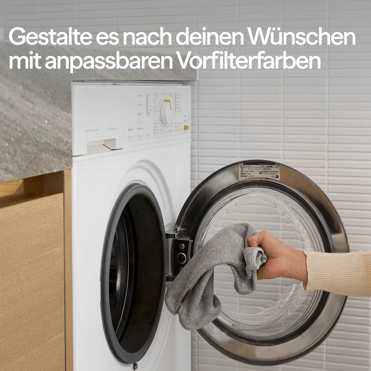 Hand legt grauen Blueair Vorfilter-Bezug in eine Waschmaschine, Werbetext zu anpassbaren Vorfilterfarben